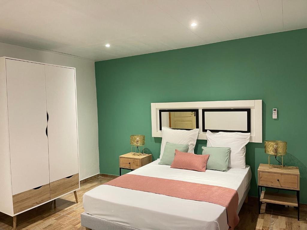 ein Schlafzimmer mit einem großen Bett mit grünen Wänden in der Unterkunft A MO TI KOTE in Guenouillet