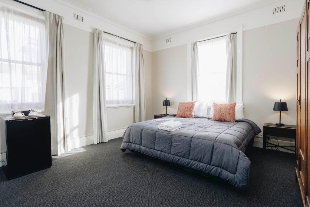 a bedroom with a bed with two lamps and windows at Hotel Gosford in Gosford