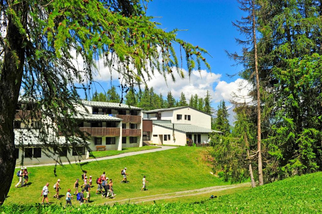 a group of people walking in the grass in front of a building at VTF Le Dou De La Ramaz in Montalbert