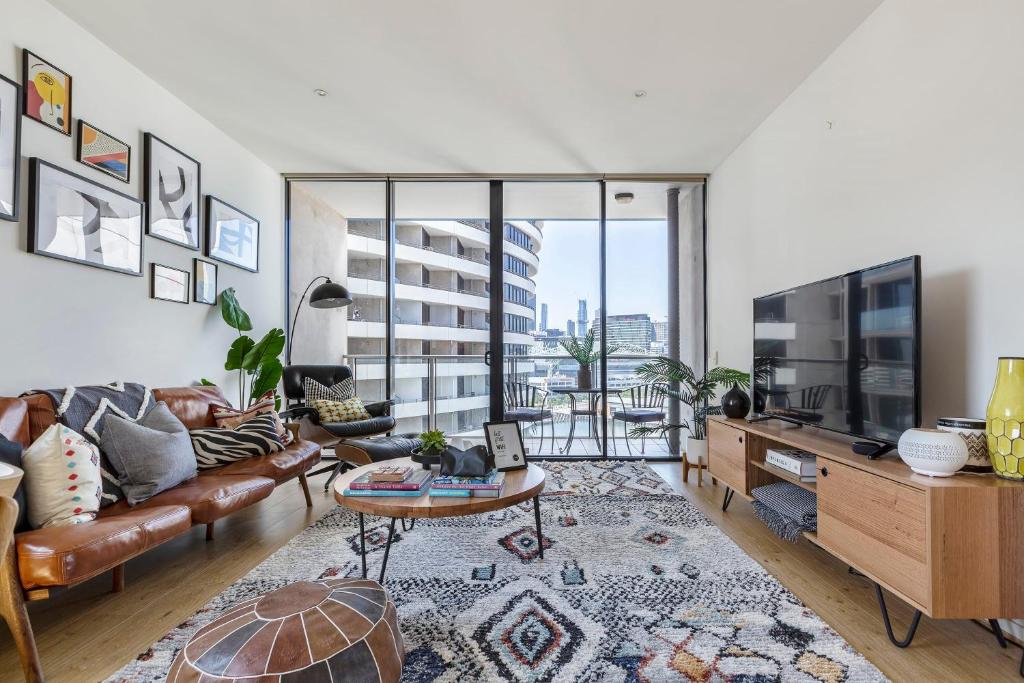 a living room with a couch and a tv at VAQUAY Scandi Boho In Docklands in Melbourne
