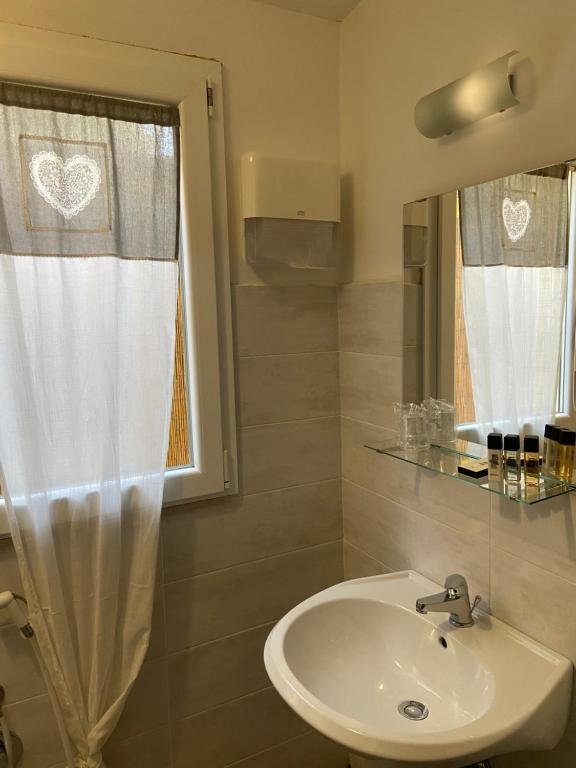 baño con lavabo y ventana con cortina en PARADISE INN en Livorno