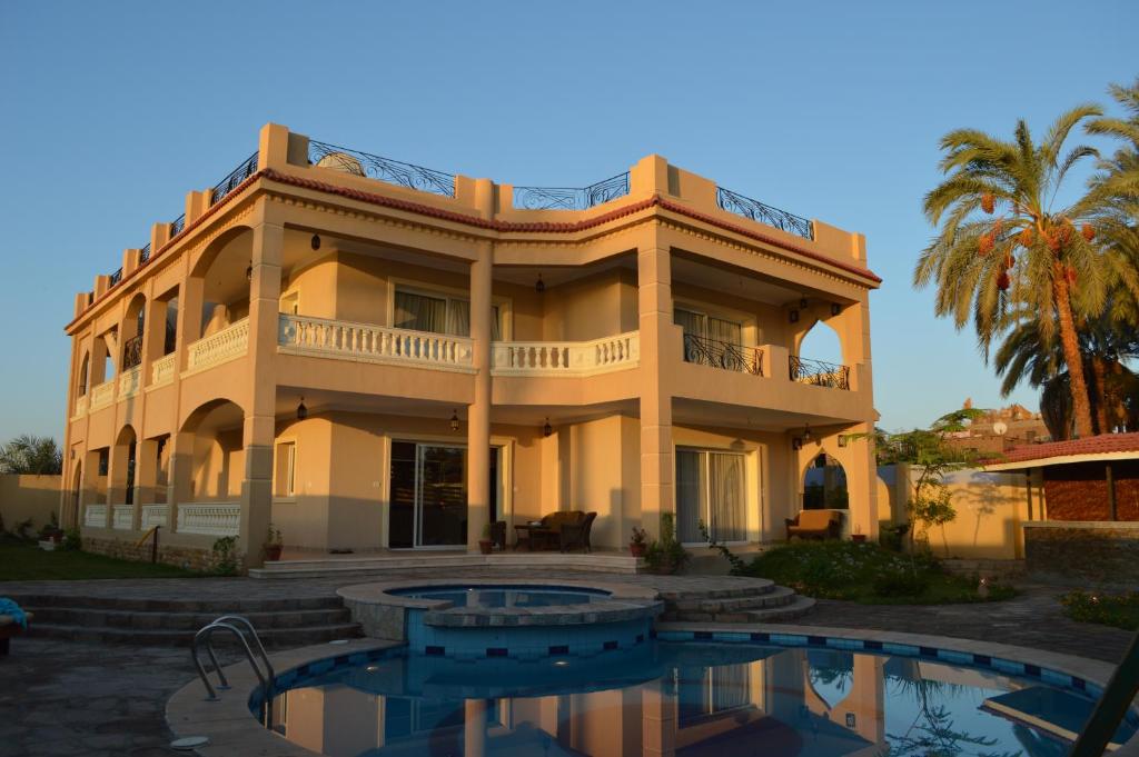 a large building with a pool in front of it at House of Hathor in Luxor