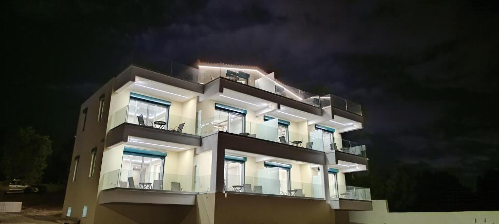 a white building with balconies at night at AIR-IN Rooms with magnificent views in Artemida