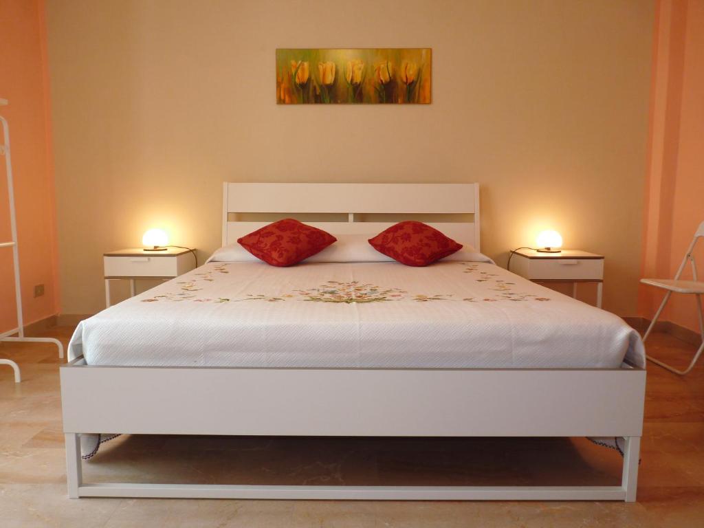 a bedroom with a white bed with two red pillows at Stanze Ad Est in Ragusa