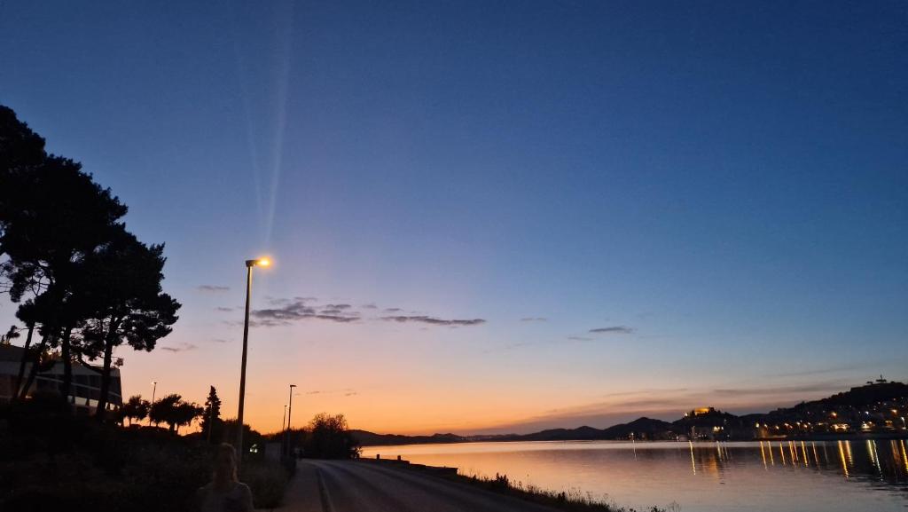 ein Straßenlicht neben einem Fluss bei Sonnenuntergang in der Unterkunft Basic Mansion Mandalina in Šibenik