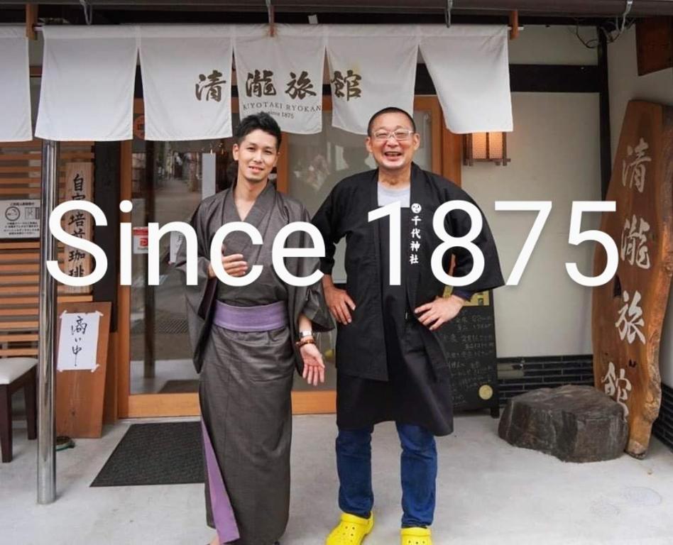 deux hommes debout devant un magasin avec le mot gingembre dans l'établissement Kiyotaki Ryokan, à Hikone