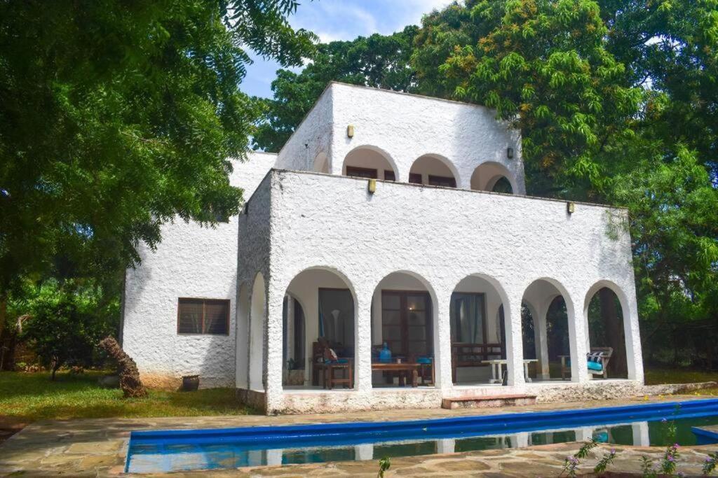 Biały budynek z basenem przed nim w obiekcie Shoreline Serenity in Malindi w mieście Malindi