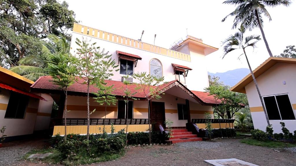 a white house with a red roof at Kuttralam Resorts in Kuttālam