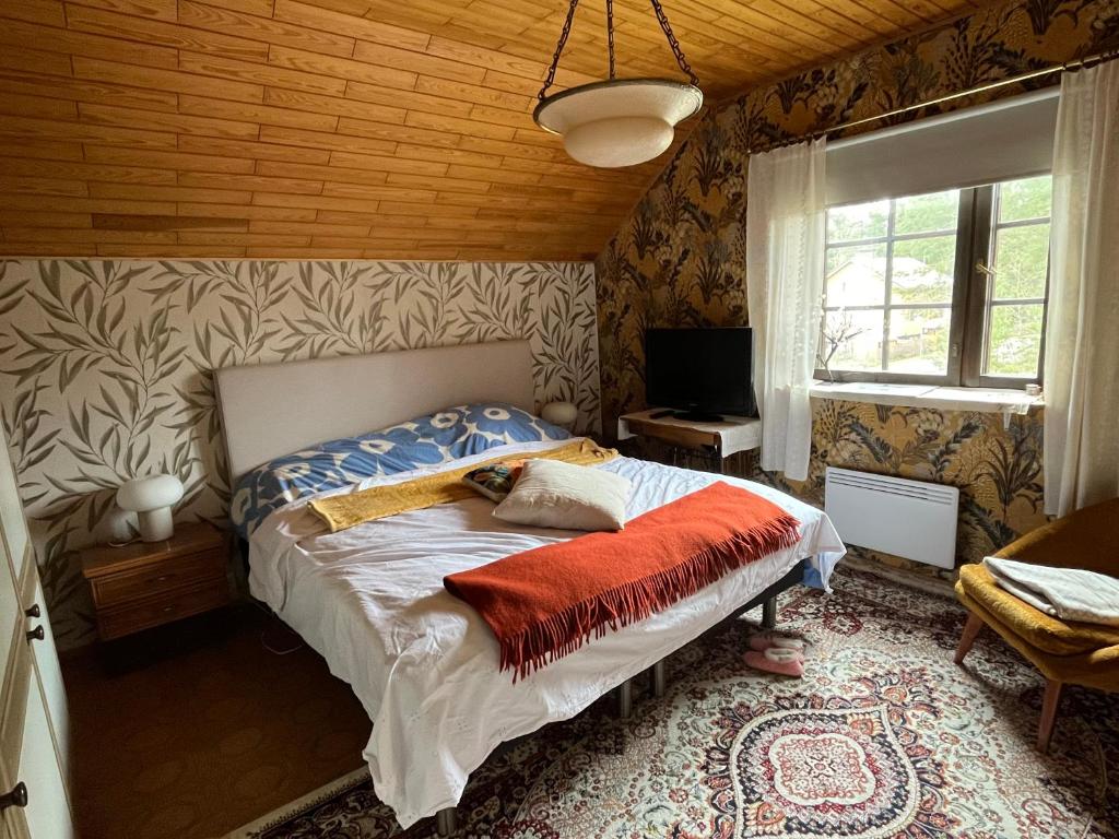 a bedroom with a bed in a room with wooden walls at Viehättävä talo Mäntässä. in Mänttä