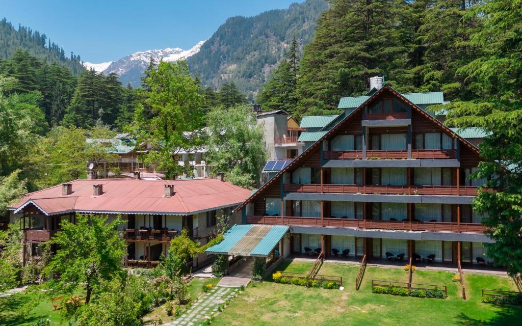 Bedzzz Xclusiv Baikunth, Manali By Leisure Hotels - 650 meters from Hidimba Devi Temple في مانالي: اطلالة جوية على مبنى كبير في الجبال