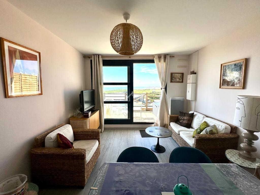 un salon avec un canapé et une télévision dans l'établissement La dérive - vue mer, à Wimereux