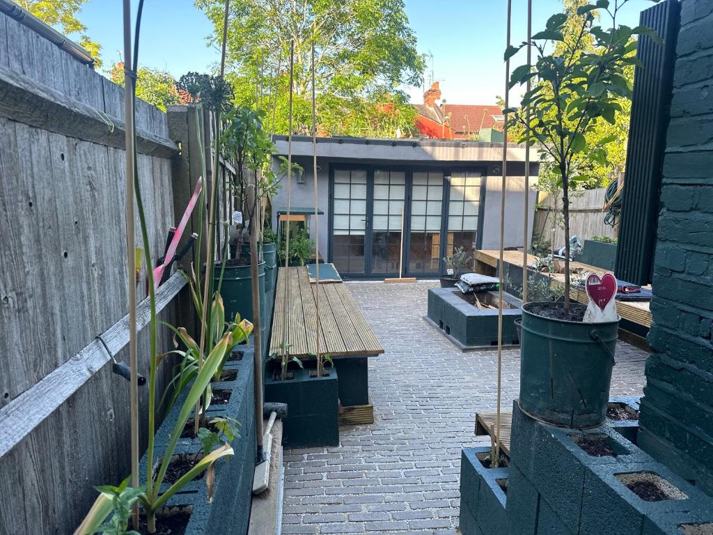 un jardin avec un banc en bois et des plantes en pot dans l'établissement Stunning 1-Bed Studio in London, à Londres