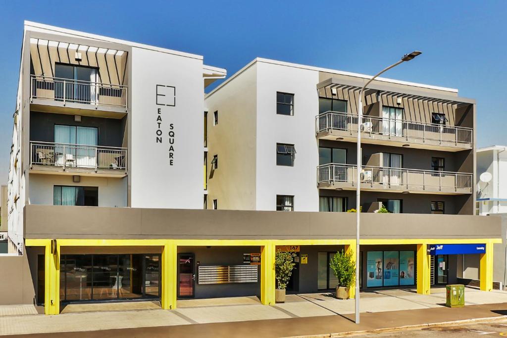 a large white building with yellow columns at WINK Aparthotel Eaton Square in Cape Town