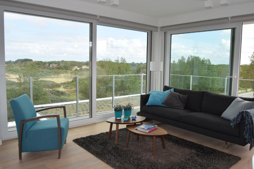 a living room with a couch and large windows at Karthuizer duinzicht in Nieuwpoort