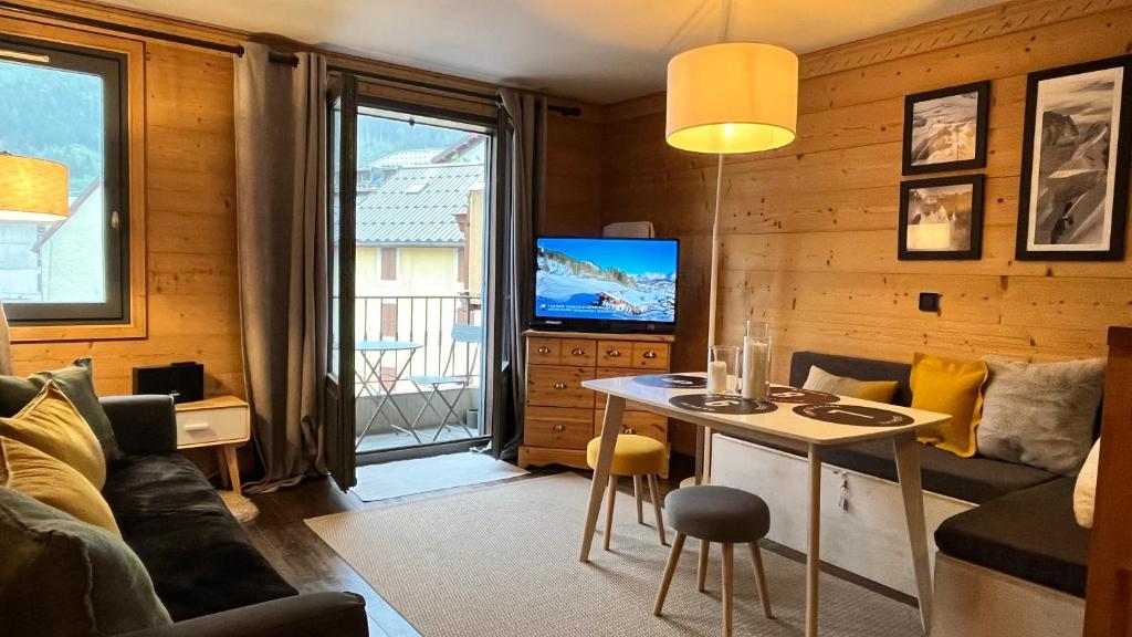 een woonkamer met een tafel en een tv bij Le 41 du Lyret - Appartement type studio pour deux avec vue sur les Aiguilles dans Chamonix Centre in Chamonix-Mont-Blanc