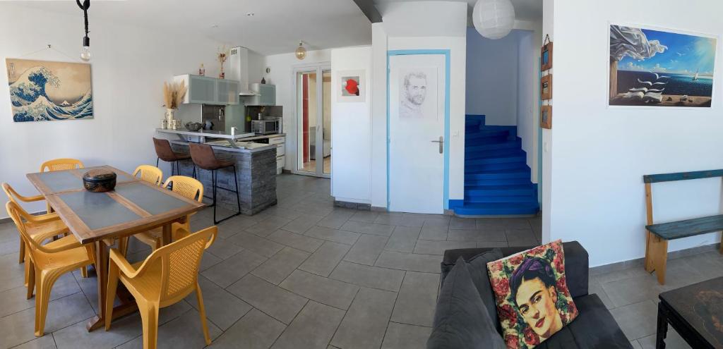 a living room with a table and chairs and a staircase at Maison climatisée au coeur de ville N1 64 in Palavas-les-Flots