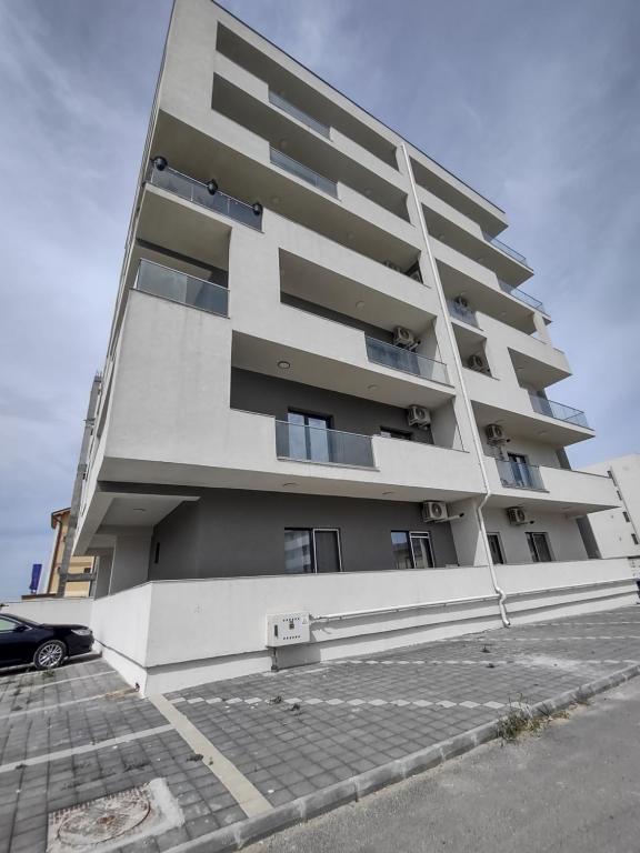 a tall white building with a car parked in front of it at Apartament Sunshine in Năvodari