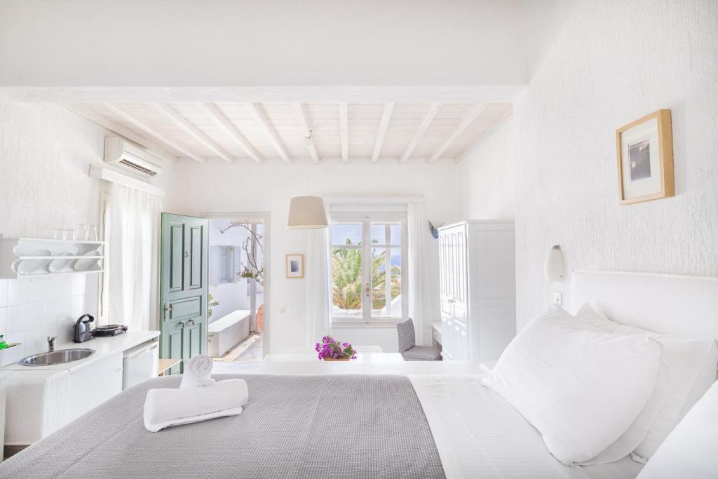 a white bedroom with a bed and a sink at Fos Apartments Mykonos in Agios Ioannis Mykonos