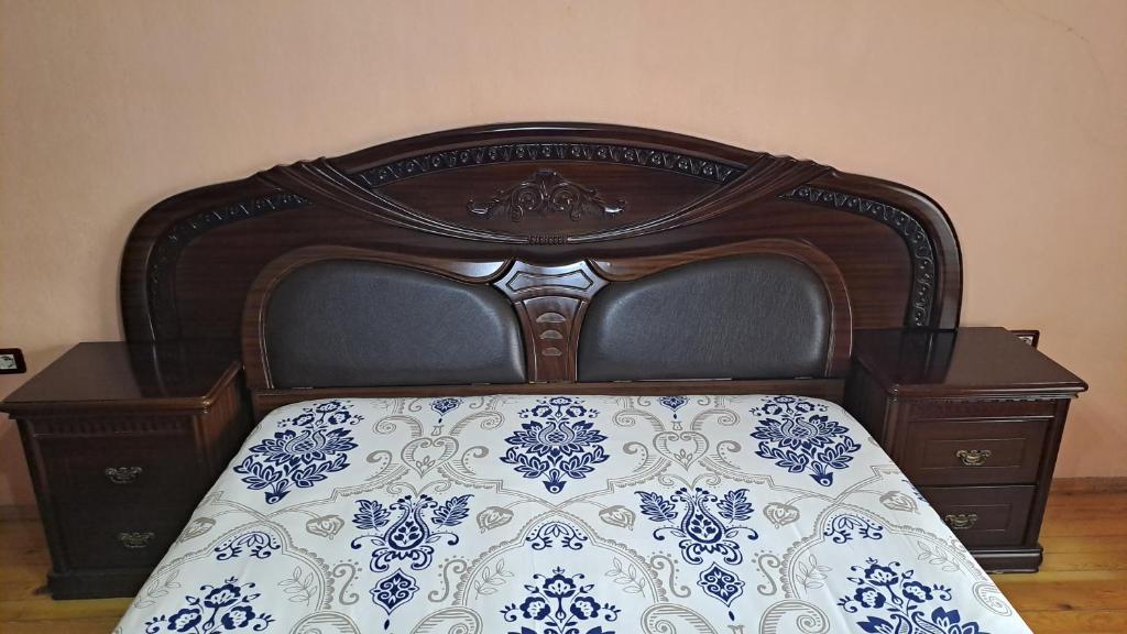 a bed with a wooden head board with a white and blue bedspread at Dream Home in Pogradec