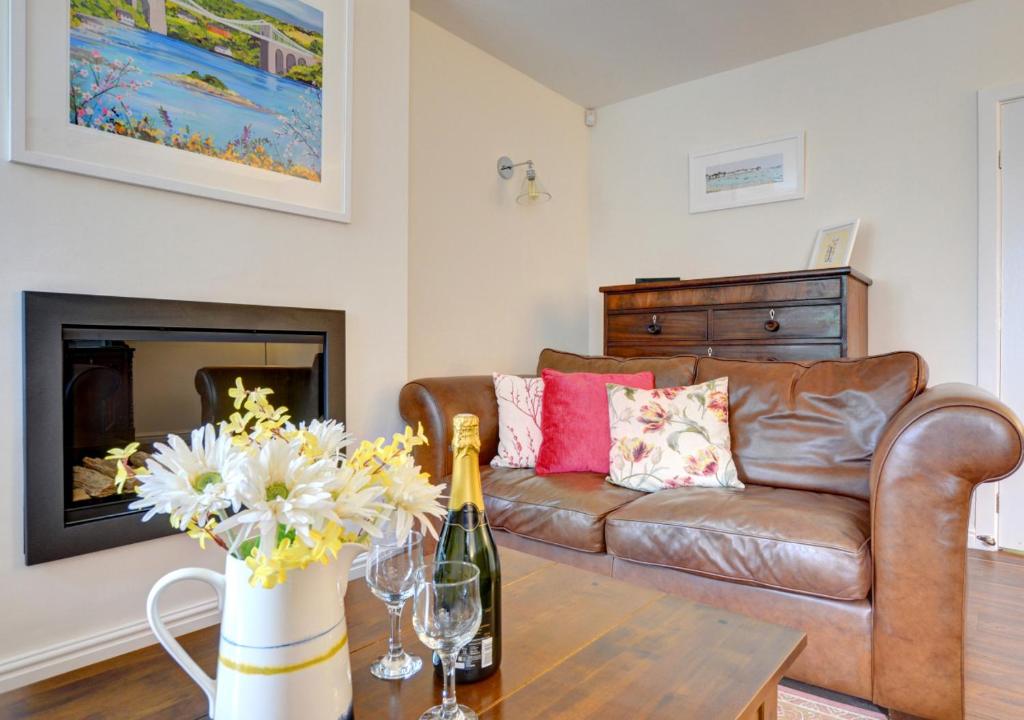un soggiorno con divano e tavolo con fiori di Hen Ysgol a Beaumaris