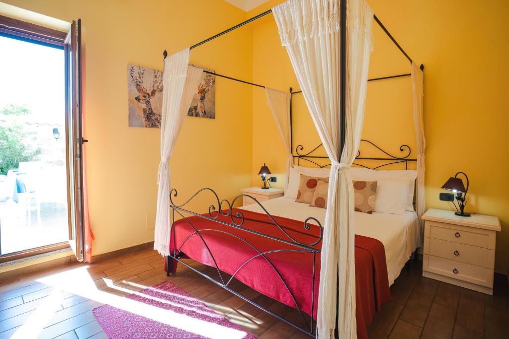 a bedroom with a canopy bed and a window at B&B L'Albero Dei Limoni in Portoscuso