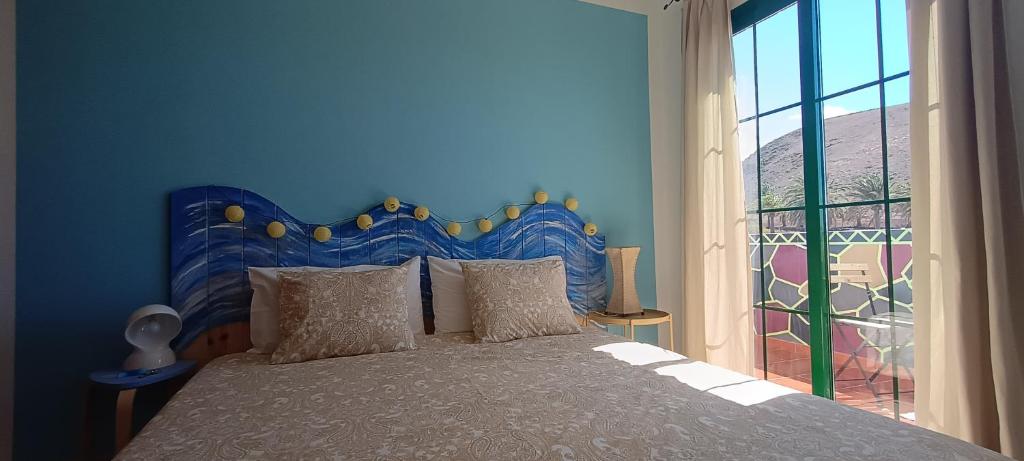 una camera blu con un letto e una grande finestra di Casa Luz a Yaiza