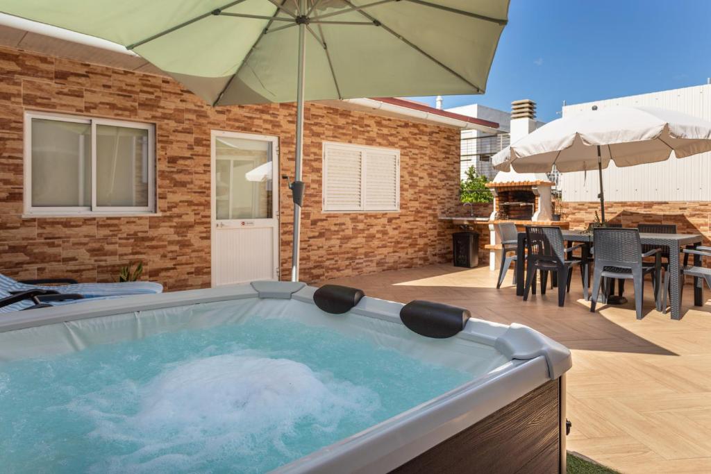 a hot tub with an umbrella on a patio at Zurrinha holidays in Quarteira