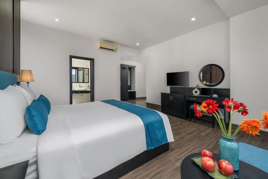 A large-bed room with a television console, dressing mirror, and small table.