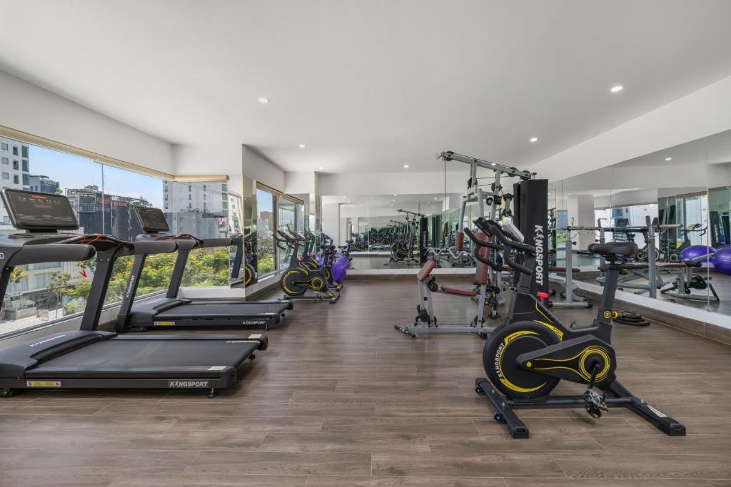 A mirrored fitness room with treadmills, bikes and a central cable-training station.