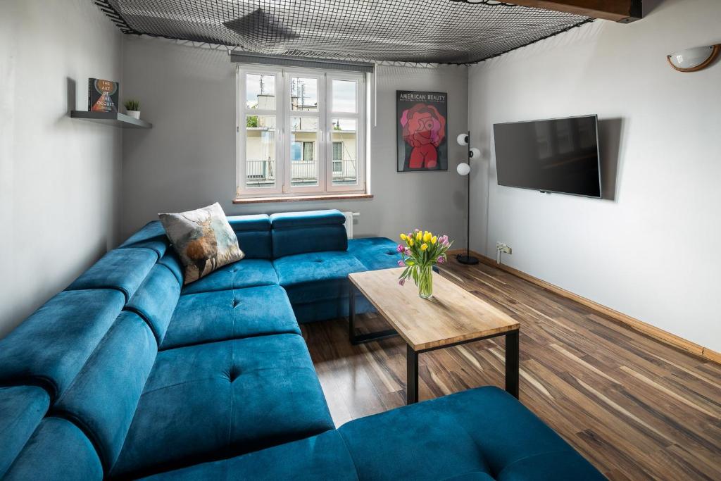 un soggiorno con divano blu e tavolo di Duplex Penthouse with hammock a Cracovia