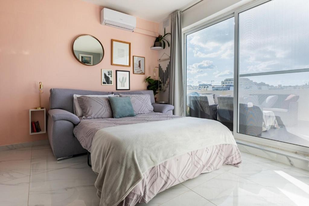 ein Schlafzimmer mit einem Bett und einem großen Fenster in der Unterkunft Bright spacious getaway close to the Sea in Gżira