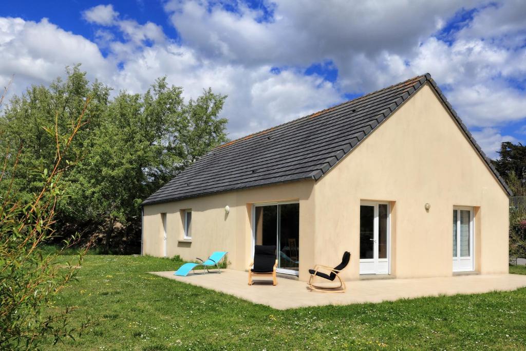 a small house with two chairs in a yard at Un tour dans la Manche - A 500 m de la plage in Portbail