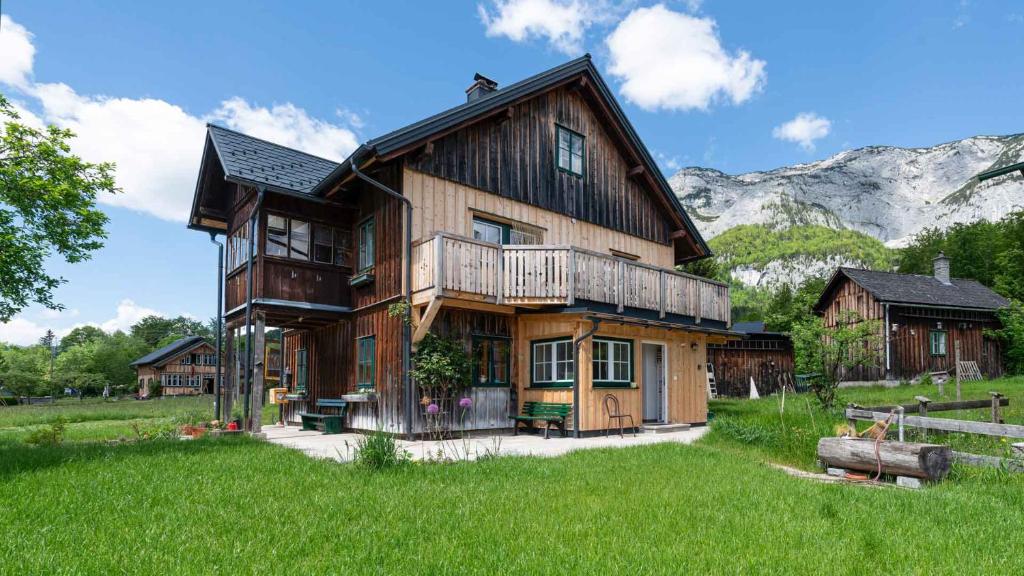 a large wooden house with mountains in the background at Ferienwohnung Haus Sonnenschein - Your Austrian Home in Grundlsee