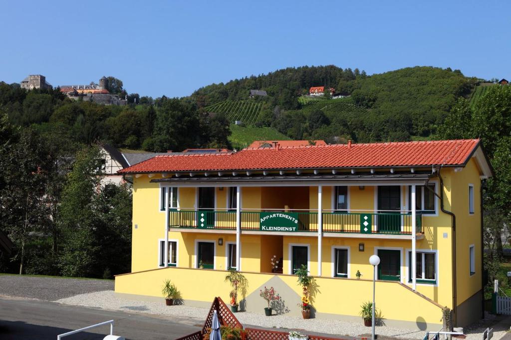 um edifício amarelo com um telhado vermelho em Apartmenthaus Franz Kleindienst em Deutschlandsberg