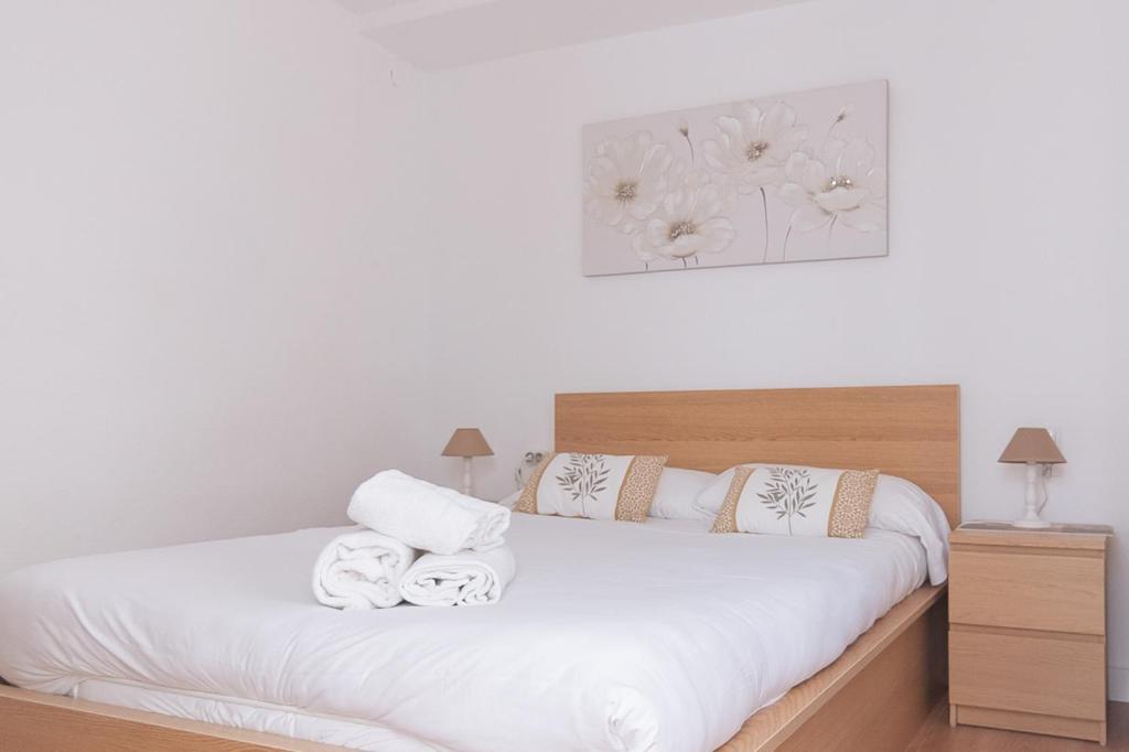 a bedroom with a white bed with towels on it at Clauhomes Oh La Lá in Tarragona