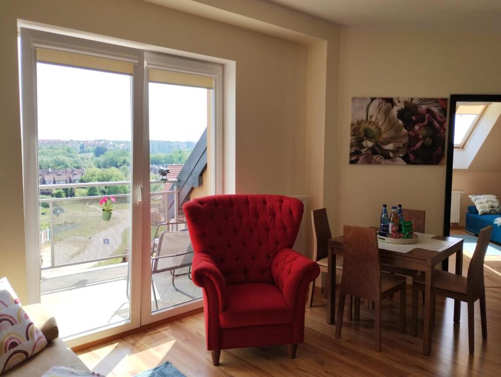 een woonkamer met een rode stoel en een tafel bij Apartament Gardena II Olsztyn Jaroty in Olsztyn