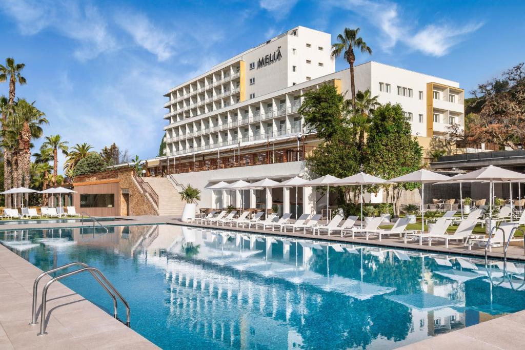 een hotelzwembad met stoelen en een gebouw bij Meliá Lloret de Mar in Lloret de Mar