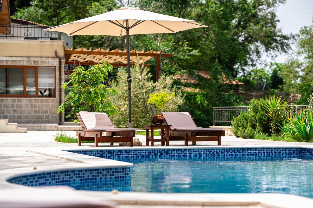 eine Terrasse mit 2 Stühlen und einem Sonnenschirm neben einem Pool in der Unterkunft Sunset & Sunrise Villas in Stanisici-Two Villas With Common Pool in Budva