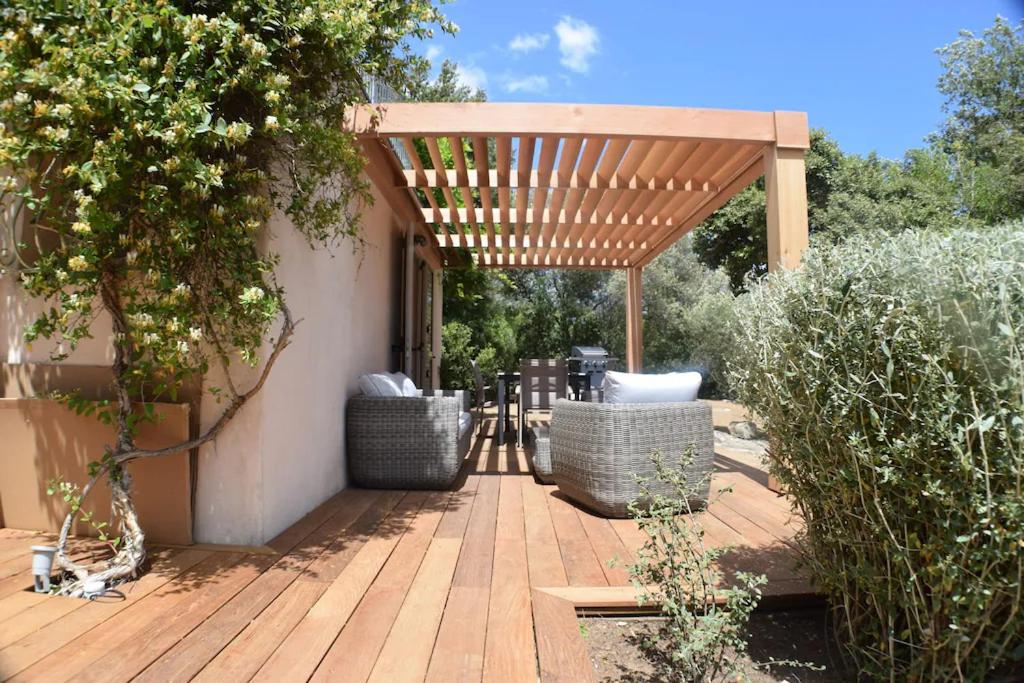 une terrasse en bois avec une pergola en bois dans l'établissement Superbe rez-de-jardin de villa MACCHIA 2, Proche des plages de Santa giulia, à Porto-Vecchio