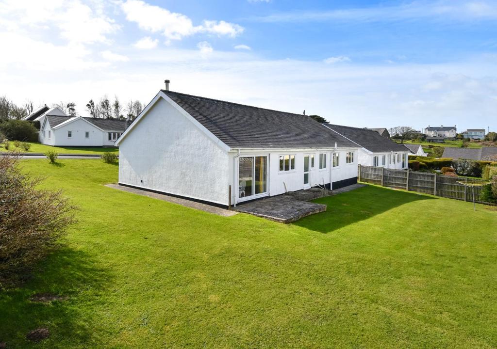 a white house with a large yard with green grass at 15 Lon Cernyw in Abersoch