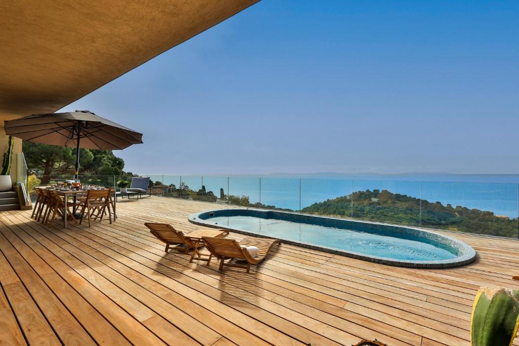 une terrasse avec une piscine, des chaises et un parasol dans l'établissement Villa Nest, à Rayol-Canadel-sur-Mer