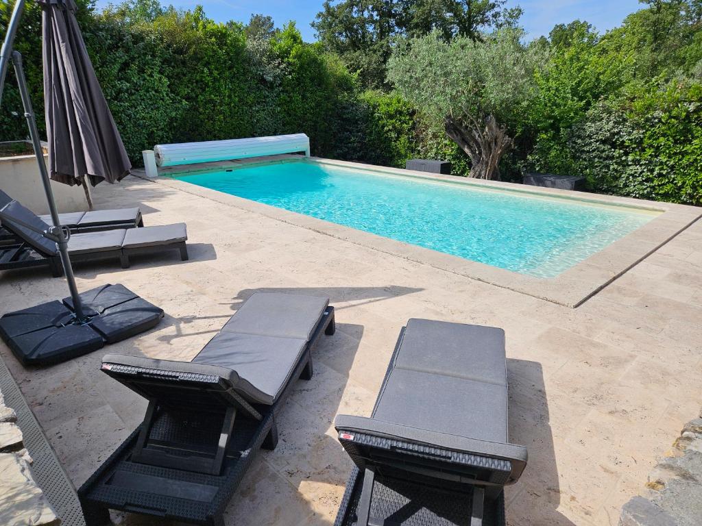 une piscine avec deux chaises longues et un parasol dans l'établissement Belle Maison Familiale 6 ou 8 personnes avec piscine, à Montauroux