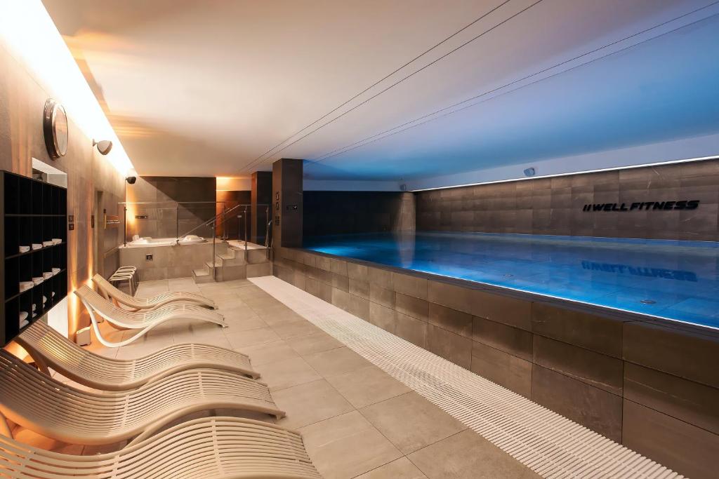 - une piscine avec bancs dans une chambre d'hôtel dans l'établissement DoubleTree by Hilton Wroclaw, à Wrocław