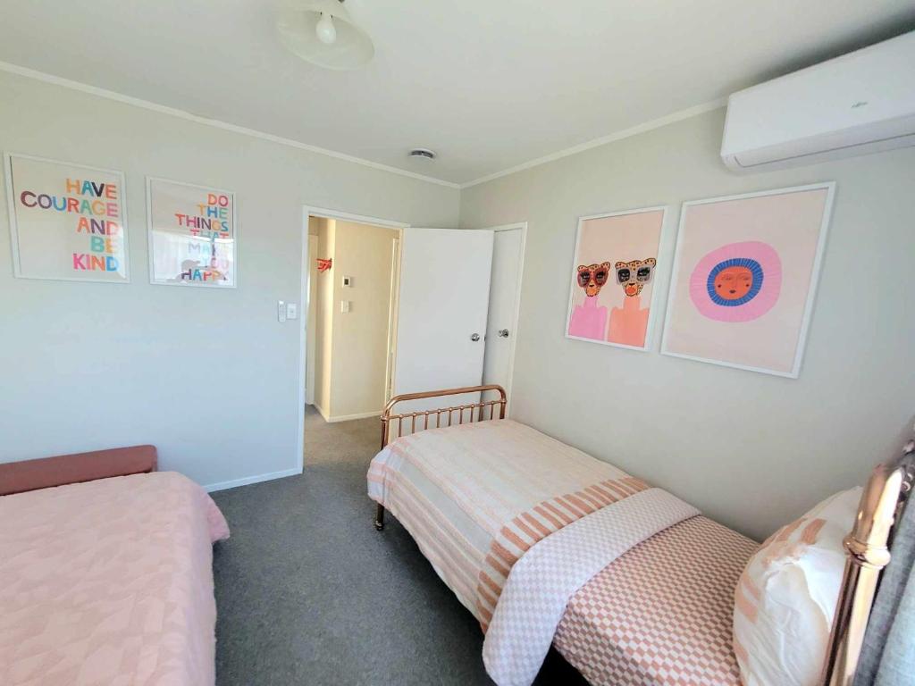 a bedroom with two beds and pictures on the wall at Aucktons house in Auckland