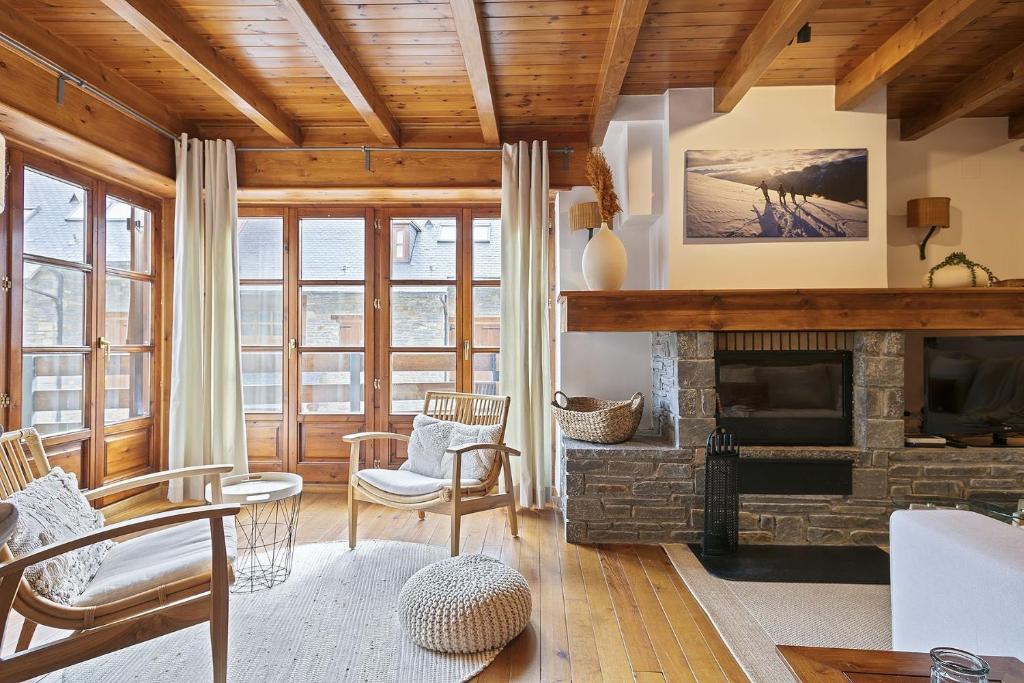 una sala de estar con chimenea de piedra y techos de madera. en Luderna - Apartamento con terraza Orri A3, en Gessa