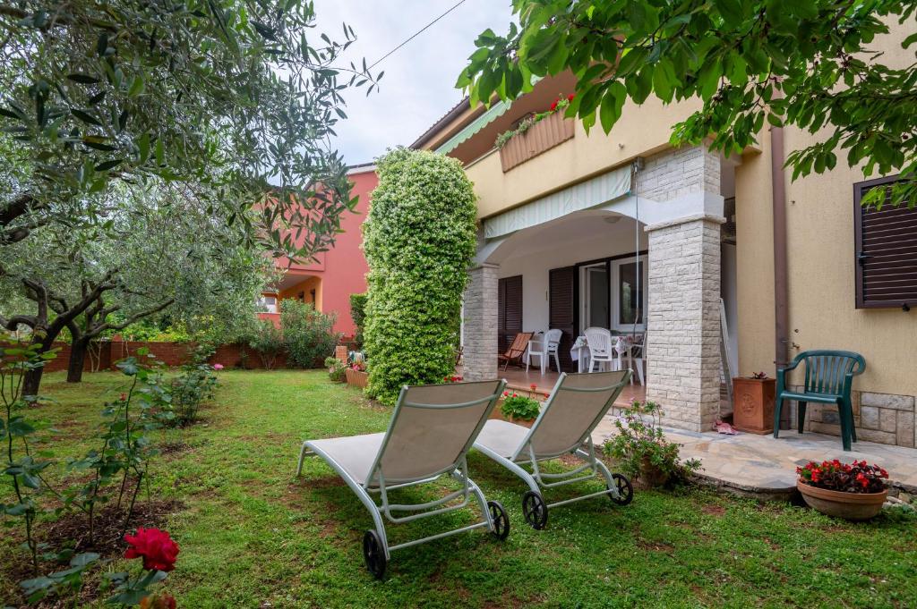 2 chaises dans la cour d'une maison dans l'établissement Apartments Mirella, à Novigrad