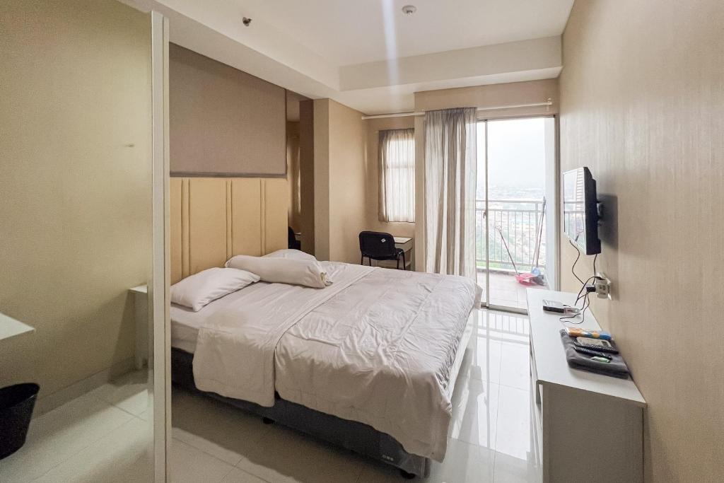 a hotel room with a bed and a window at RedLiving Springwood Residence - Living space in Warungmangga