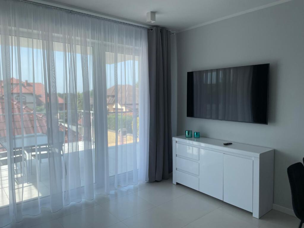 Televízia a/alebo spoločenská miestnosť v ubytovaní Apartamenty AQUA MAZURY