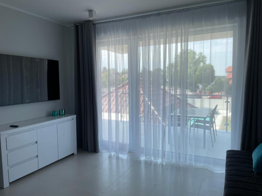 Televízia a/alebo spoločenská miestnosť v ubytovaní Apartamenty AQUA MAZURY
