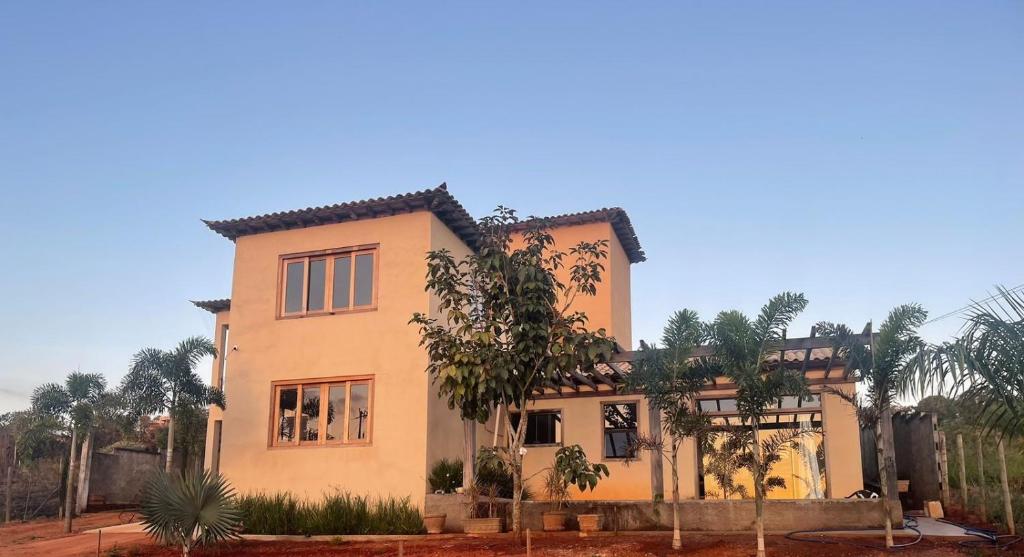 une grande maison jaune avec des arbres devant elle dans l'établissement Pousada Canto da Seriema, à Tiradentes